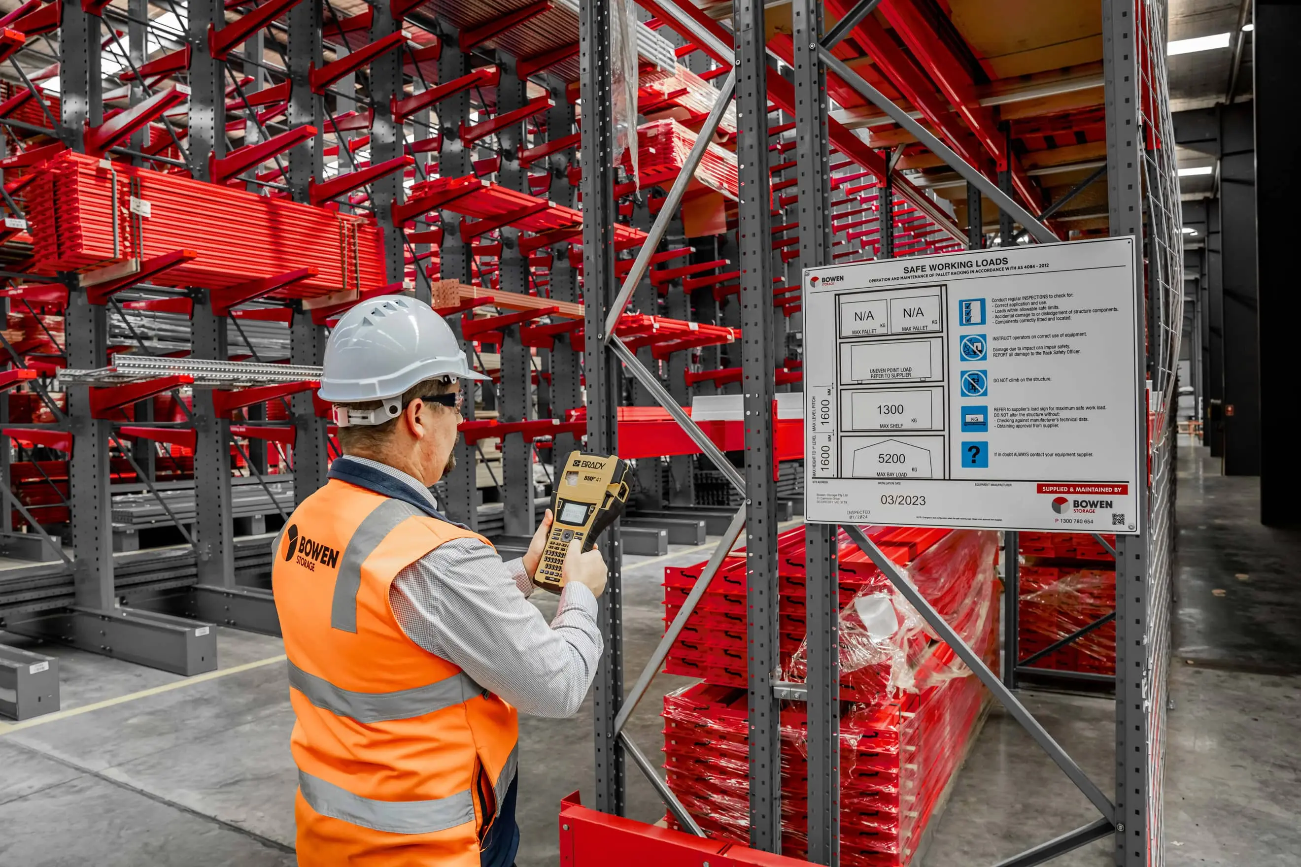 Warehouse worker inspecting pallet racking and checking load information during a rack inspection.